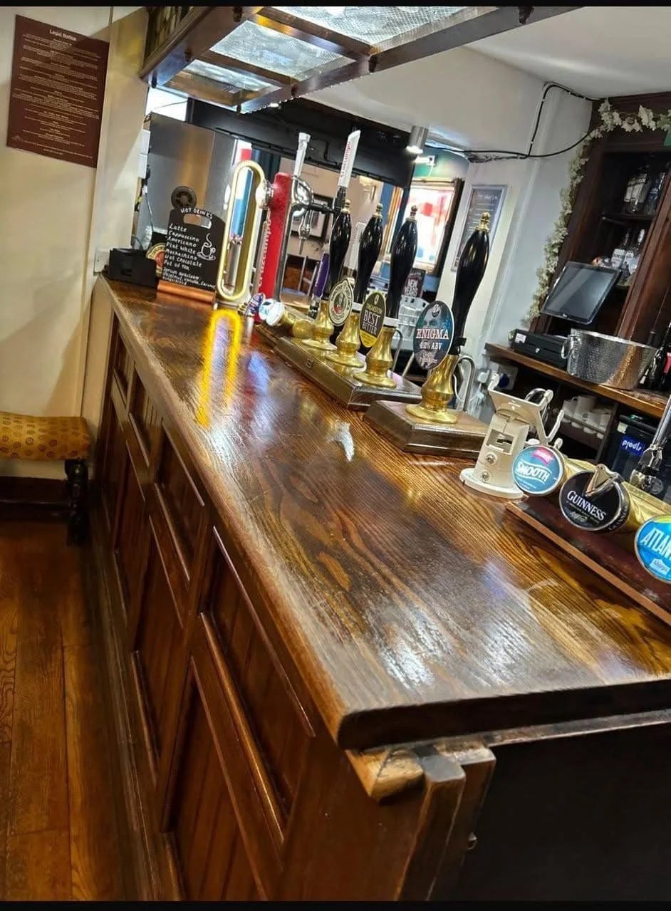 Polished pub bar with beer taps and a clean wood top