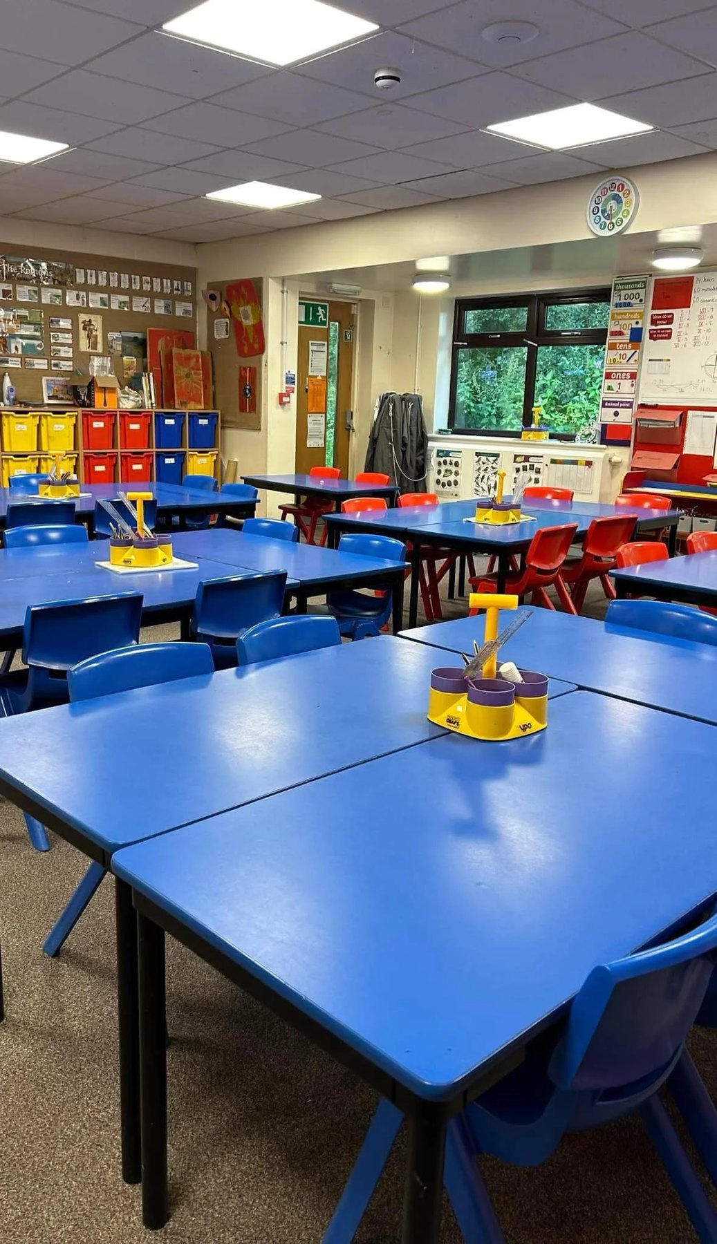 Cleaned primary classroom with blue tables, chairs and vacuumed carpet